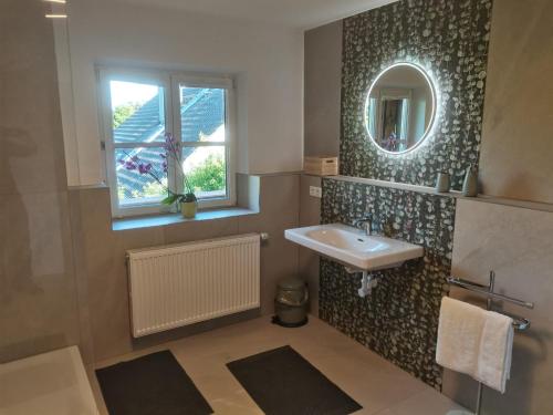 ein Badezimmer mit Waschbecken, Fenster und Spiegel in der Unterkunft Grey House in Laufen