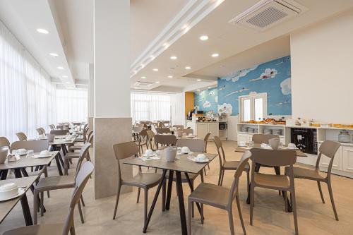 a restaurant with tables and chairs and a kitchen at Hotel Geminus B&B in Cesenatico