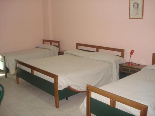 a hospital room with three beds with white sheets at Hotel Grandinetti in Parenti