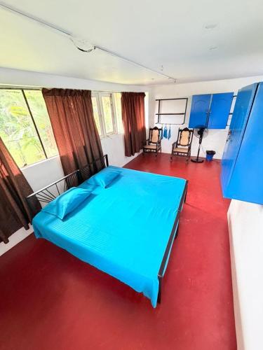 a bedroom with a blue bed and a red floor at Coca Cola Hostel Malabe in Malabe