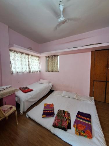 a room with two beds and a table and windows at Siddhi Home Stay in Kolhapur