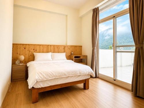 a bedroom with a bed and a large window at Songfeng B&B in Luye