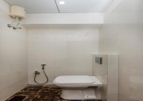 a white bathroom with a toilet and a shower at Hotel Cliff Hanger in Mumbai