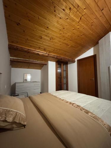 a bedroom with a large bed with a wooden ceiling at da rifare 1 in Solto Collina