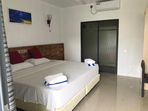 a bedroom with a large white bed with towels on it at Zukara Maldives in Thoddoo