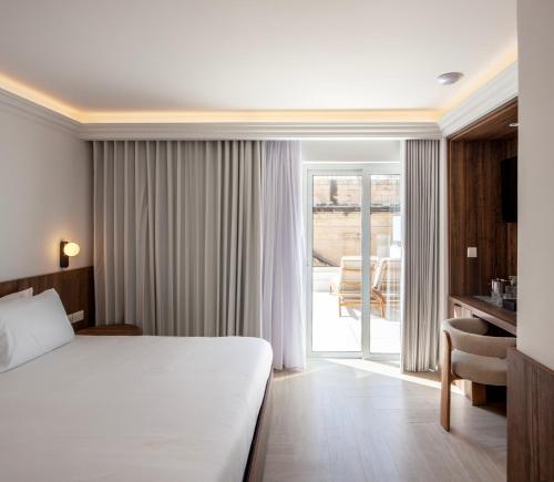a hotel room with a bed and a sliding glass door at The Republic Boutique Hotel in Valletta
