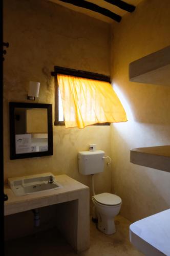 a bathroom with a toilet and a sink and a window at Amu House in Lamu