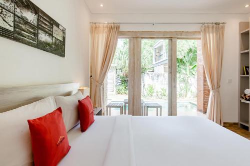 a bedroom with a large white bed with red pillows at Nyang-Nyang Retreat in Uluwatu