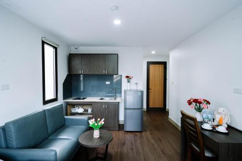 a living room with a blue couch and a kitchen at Granda Hanoi Hotel & Apartment in Hanoi