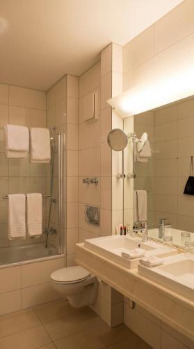 a bathroom with a sink and a toilet and a shower at guestified GRAND AIRPORT Hotel Düsseldorf Ratingen in Ratingen