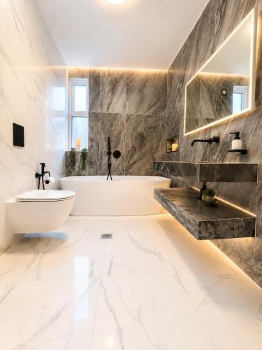 a bathroom with a white tub and a sink at Luxurious & Elegant 6-Bed House in Barnet