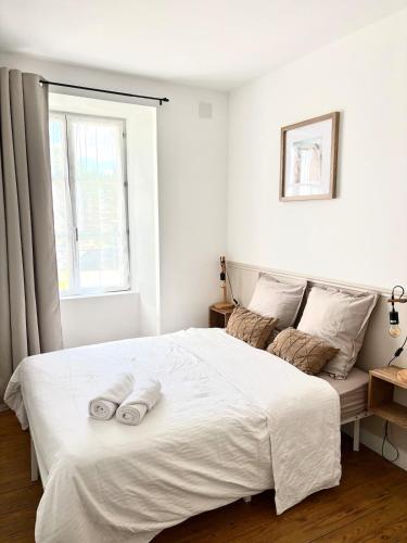 a bedroom with a large white bed with towels on it at appartement mauléon in Mauléon