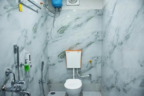 a bathroom with a white toilet and a marble wall at S S Plaza in mayapur
