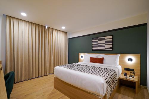 a bedroom with a large bed and a green wall at Olive Hotel JP Nagar Metro by Embassy Group in Bangalore