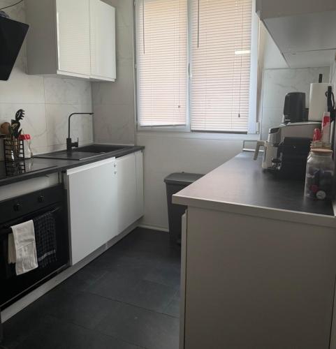 a kitchen with white cabinets and a black stove at Location dans résidence privée,sécurisée ,parking gratuit , 1 minute du tramway, à 9 minute du centre ville, accessible à plusieurs transports in Nice