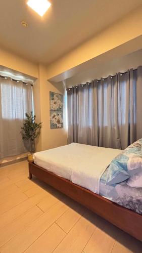 a bedroom with a bed and a window with curtains at The Mactan Newtown in Punta Engaño
