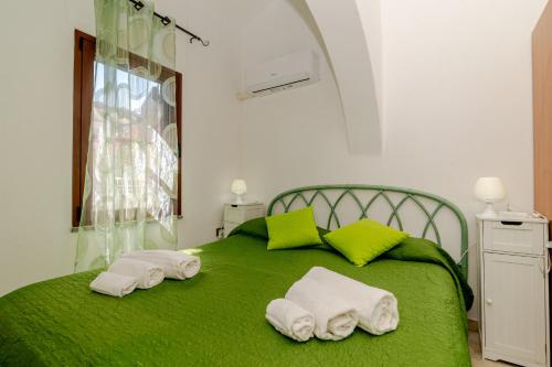 a green bed with two towels on top of it at San Teodoro Monti22 vicino spiaggia in San Teodoro