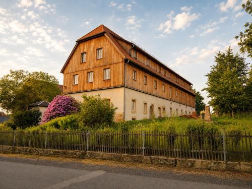 a large wooden building on a hill with a fence at Gutshof 1600 in Hohnstein