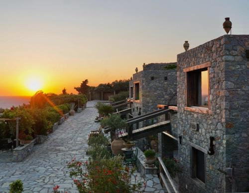 a stone building with a sunset in the background at Terra Minoika Boutique Resort in Kato Zakros
