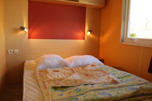a bed in a bedroom with orange walls and a window at Camping de la Rive in Notre-Dame-de-Monts