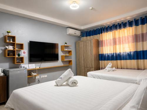 a hotel room with two beds and a flat screen tv at Valentine Hotel Angeles City managed by Cocotel in Angeles