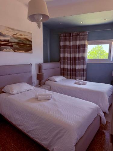 a bedroom with two beds and a window at GA apartments in Kato Pyrgos