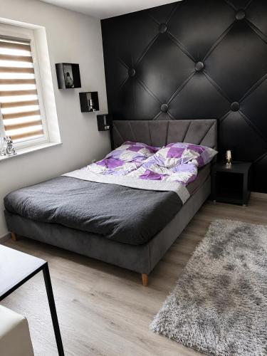 a bedroom with a large bed with a black headboard at Móra Apartman in Pécs