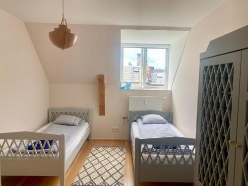 two beds in a small room with a window at Central Penthouse with Private Rooftop Terrace in Copenhagen