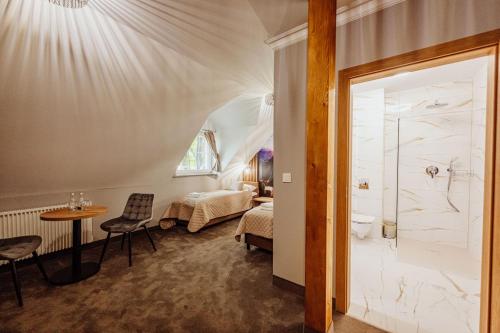 ein Zimmer mit einem Bett, einem Tisch und einem Badezimmer in der Unterkunft Lekkoduch in Świeradów-Zdrój