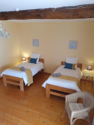 a room with two beds and a chair in it at La Grange Fleurie in Tramayes