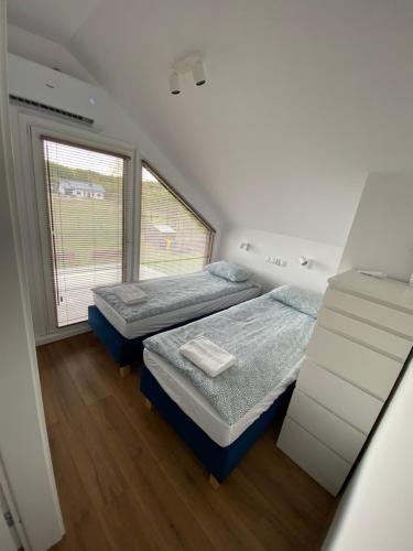 a bedroom with two beds and a window at Domki Osada Wałpusz dom bliźniak in Zielonken