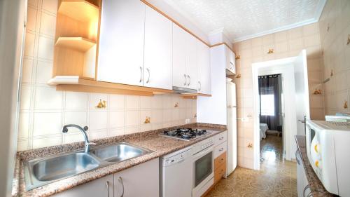 a white kitchen with a sink and a stove at Villa Mª José in Benicarló
