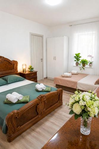 a bedroom with two beds and a vase of flowers at Hana Skadar Lake - 200 metara do jezera in Prevlaka