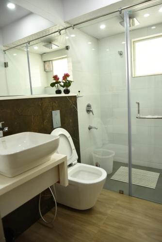a bathroom with a sink and a toilet and a shower at Aditya Homes Gachibowli in Hyderabad