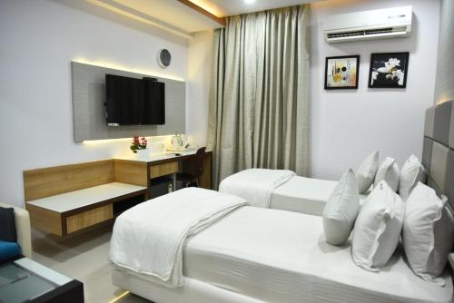 a hotel room with two beds and a desk at Aditya Homes Gachibowli in Hyderabad
