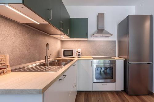 a kitchen with white cabinets and a stainless steel refrigerator at Maison Bovet Appartements in Arvier
