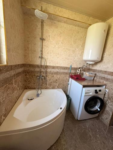 a bath tub in a bathroom with a washing machine at Little house Kazbegi in Kazbegi