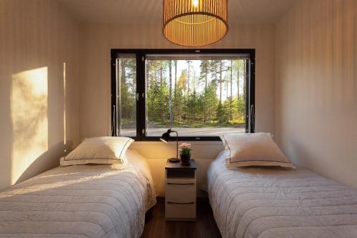 two beds in a room with a window at Villa Karina - Beachfront with Jacuzzi in Porvoo