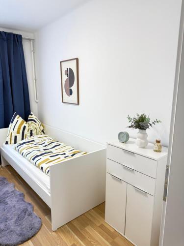 a white bedroom with a bed and a dresser at TSD Living in Kapfenberg