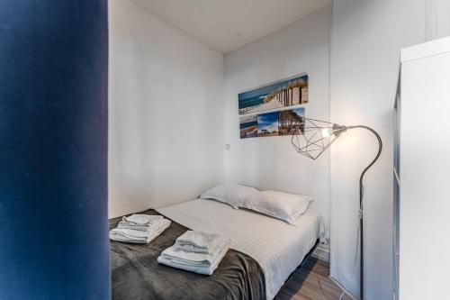 a white bedroom with a bed and a lamp at Appartement Le Mauresque in Arcachon
