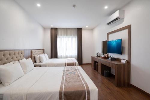 a hotel room with two beds and a television at MOMALI Hotel Ninh Binh in Ninh Binh