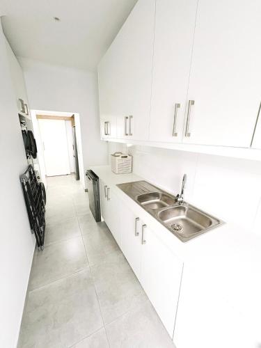 a kitchen with white cabinets and a sink at Villa Jabulani in Stompneusbaai