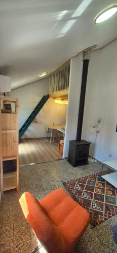 a living room with an orange chair and a staircase at Studio Juncalinho - Stylish Portuguese Studio in São Teotónio