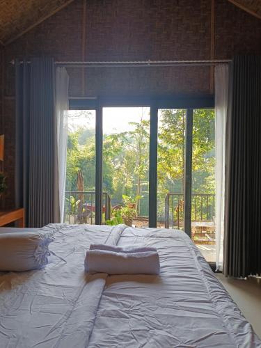 a large bed in a room with a large window at Bunga Lodge Tetebatu in Tetebatu