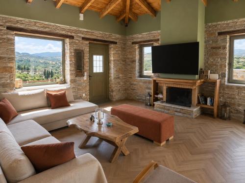 a living room with a couch and a tv at Bellevia Stone Pool Villa in Kouvéllai