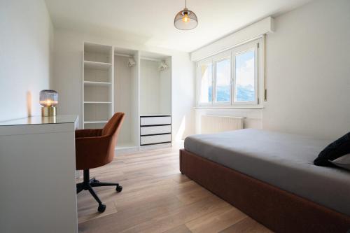 a bedroom with a bed and a desk and a chair at La vue Appartement Gruyère in Bulle