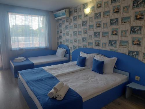 a blue bedroom with two beds and a window at Къща за гости КАТИ in Kiten