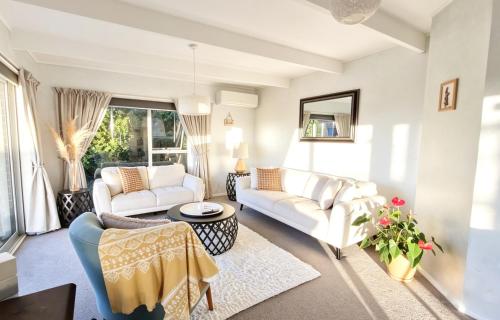 a living room with two couches and a table at Clifftop Coastal Retreat with Ocean Views - Close to Beach & Cafés in Auckland