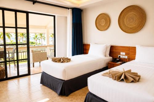 two beds in a hotel room with a balcony at Golden Sands Destination Resorts in Daanbantayan