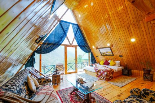 a living room with a large window and a couch at Himalayan Manor A-Frame Cabin in Sainj